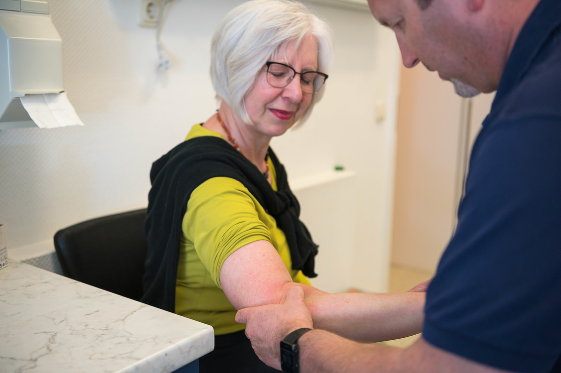 Dr. Wolf untersucht den Arm einer Patientin